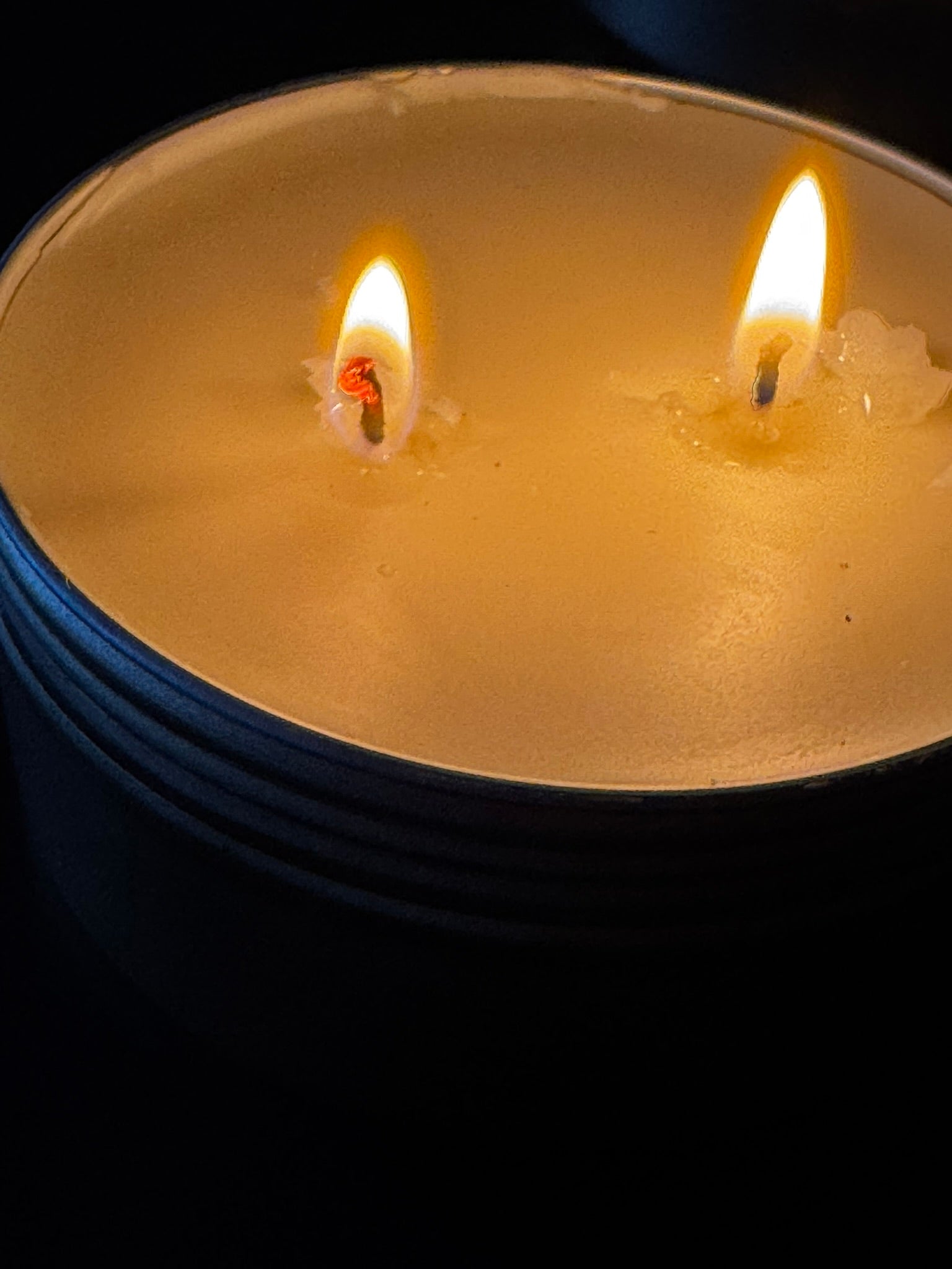 Close-up of a double-wick candle with flames against a dark background
