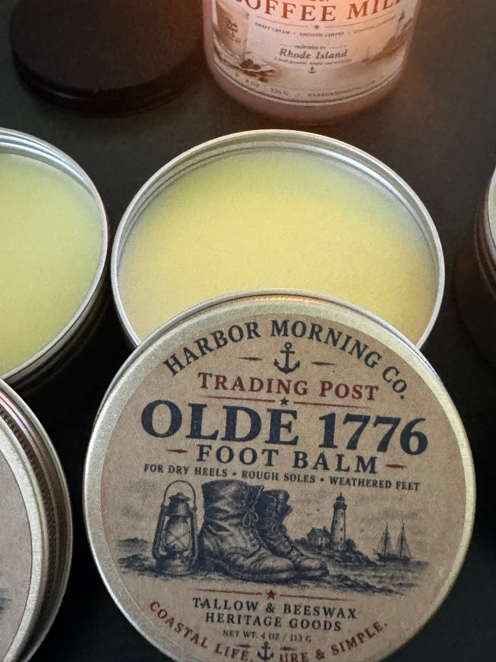 Foot balm container with 'Harbor Morning Co.' branding on a dark surface.