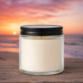 Harbor Morning Co. Beach Sunset 4oz hand-poured coastal soy candle on a wooden surface with ocean sunset in the background