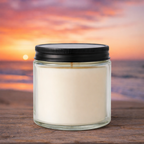 Harbor Morning Co. Beach Sunset 4oz hand-poured coastal soy candle on a wooden surface with ocean sunset in the background