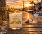 Harbor Morning Co. Golden Boardwalk 8oz hand-poured coastal soy candle with a Gulf Coast boardwalk sunset scene — seagull, palm trees, and beachside businesses in the background