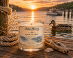 Harbor Morning Co. Quiet Cove 8oz hand-poured coastal soy candle on a pier with weathered boat rope, driftwood, seashell, fishing boat, and duck swimming at sunrise
