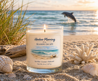 Harbor Morning Co. Seaside Escape 8oz hand-poured coastal soy candle on sandy beach with seashells, driftwood, sea grass, and dolphin jumping in the background