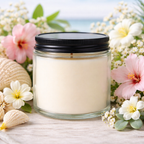 Harbor Morning Co. Tidal Bloom 4oz hand-poured coastal soy candle surrounded by beach flowers with ocean in the background